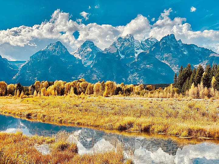 Mountains with orange colored tree leaves and a river